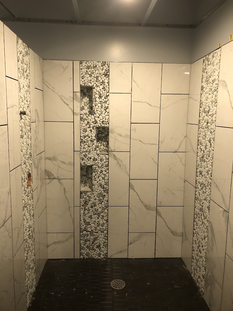 Marble shower with vertical pebble accent and recessed niches
